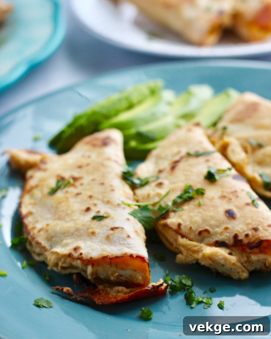 A generous platter of golden-baked chicken taquitos, with a bowl of vibrant green guacamole and fresh pico de gallo, inviting a delicious feast.