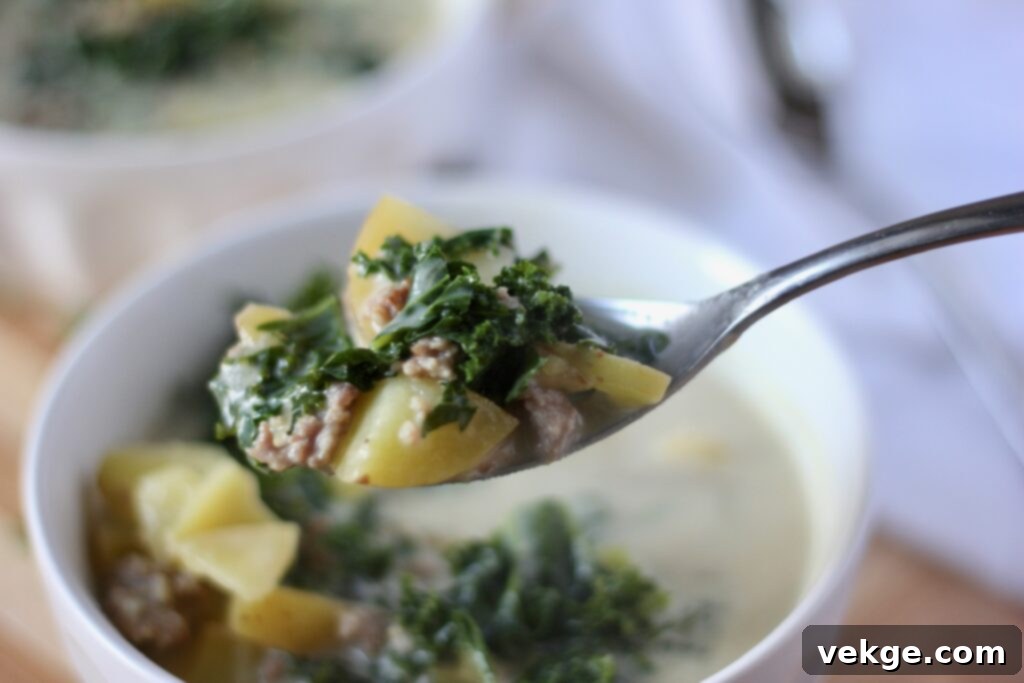 Close-up of fresh ingredients for Zuppa Toscana, including onion, garlic, sausage, and kale.