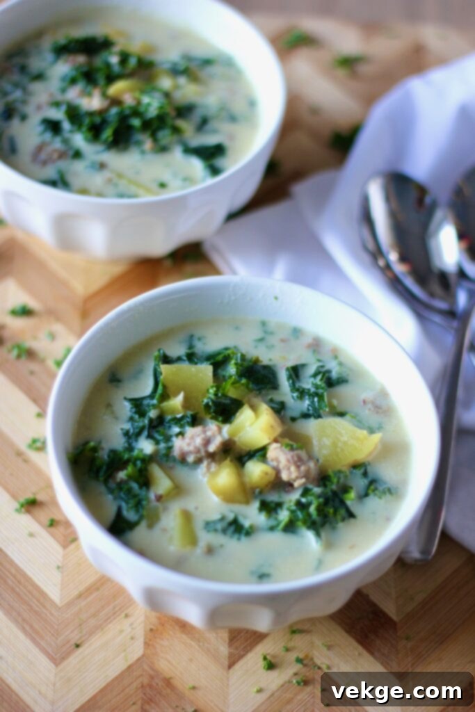 A large pot of Zuppa Toscana simmering on the stove, showing the rich broth, sausage, potatoes, and kale.