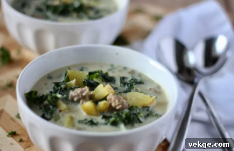 A bowl of creamy Zuppa Toscana soup with sausage, potatoes, and kale, garnished with fresh herbs.