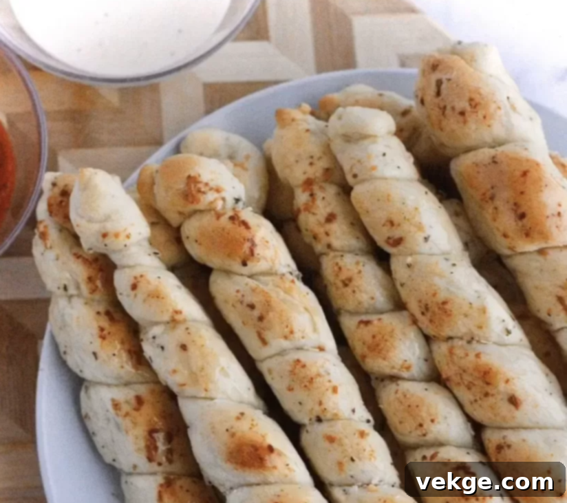 Golden Cheesy Swirls 3 Close-up of baked cheesy bread twists on skewers, showing golden crust and melted cheese.