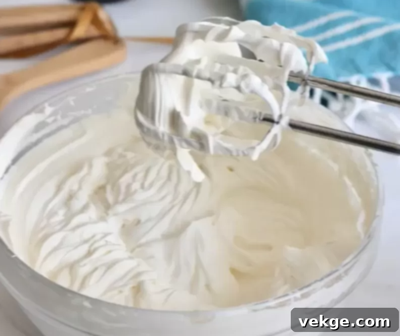 A bowl of freshly made sweetened whipped cream, featuring a smooth, delightful texture and ready to be served.