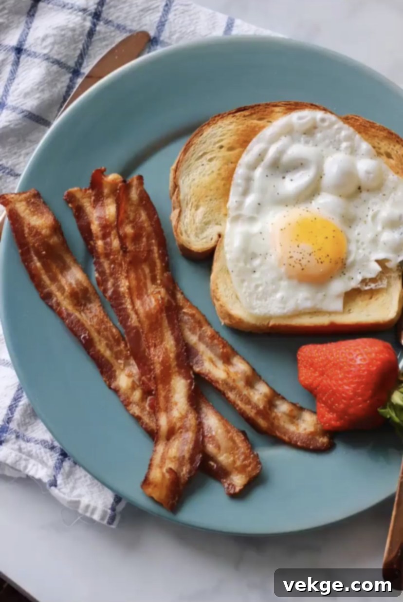 Crispy oven-baked bacon strips on a baking sheet, glistening with rendered fat and ready to be served