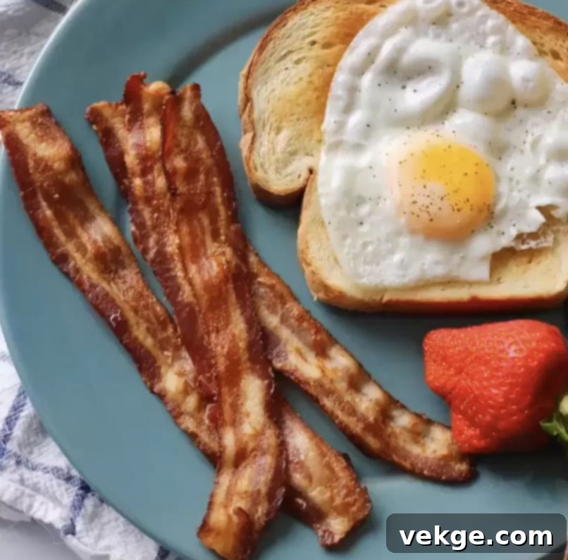 A close-up of a plate filled with golden-brown, perfectly cooked crispy bacon strips.