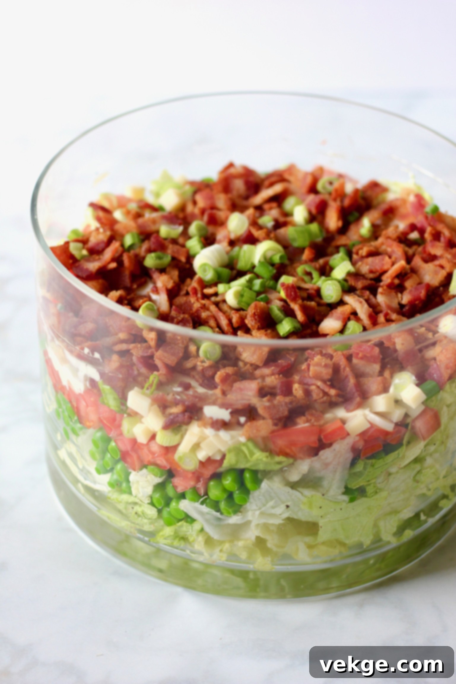 layered salad in a glass bowl with a serving taken out