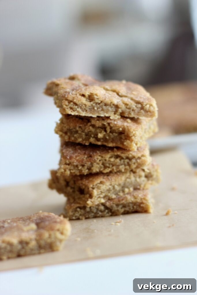 Freshly baked snickerdoodle bars cooling in a sheet pan, showing their perfectly wrinkled cinnamon-sugar topping and golden-brown edges.