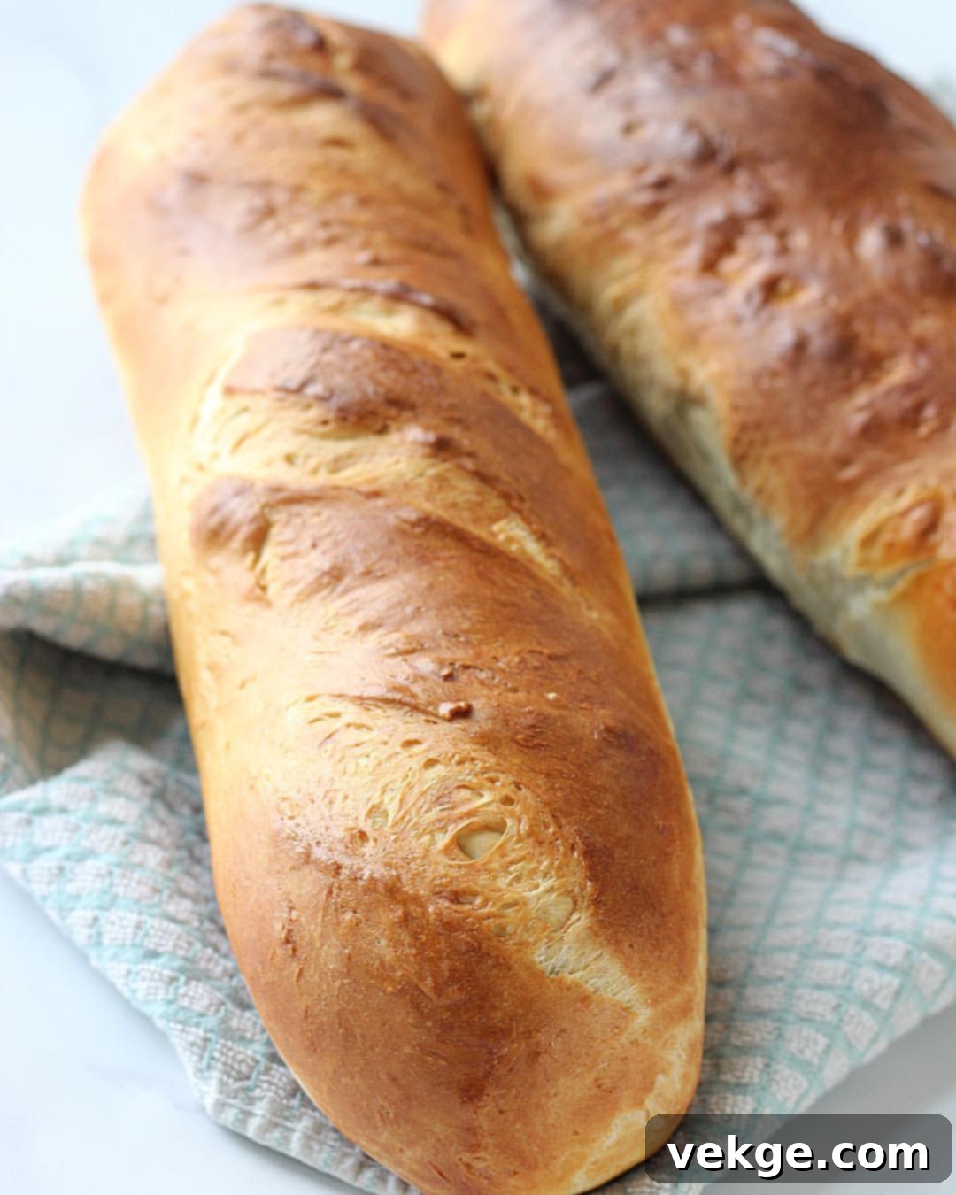 Fluffy and Chewy French Bread Perfection 2 Two freshly baked loaves of golden-brown, soft and chewy French bread on a baking sheet, ready to be enjoyed.